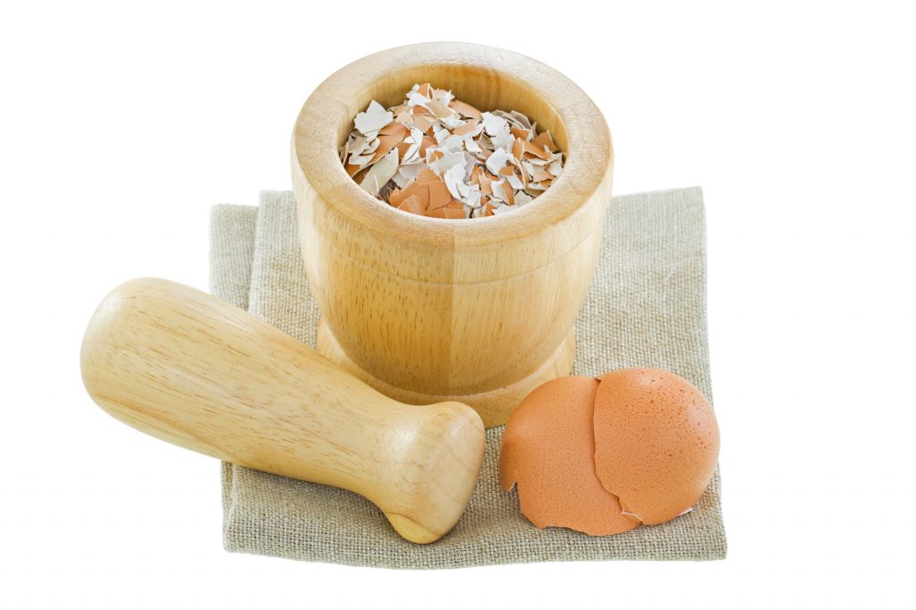 crushed eggshells inside a wooden mortar and pestle